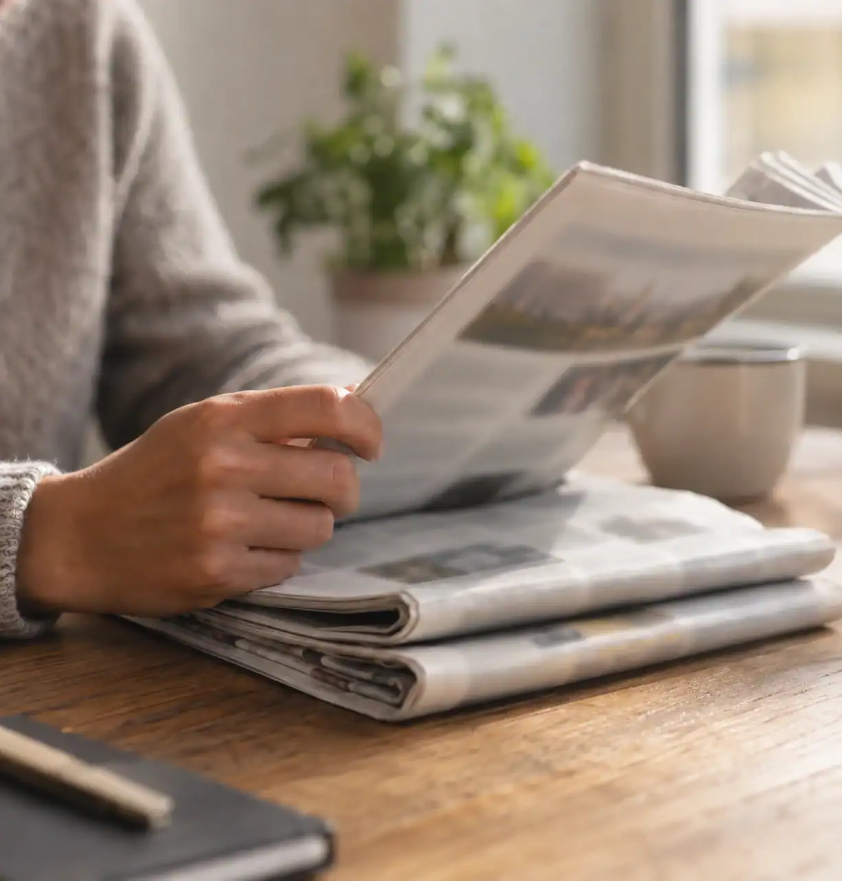 Une personne lit un journal imprimé à une table.